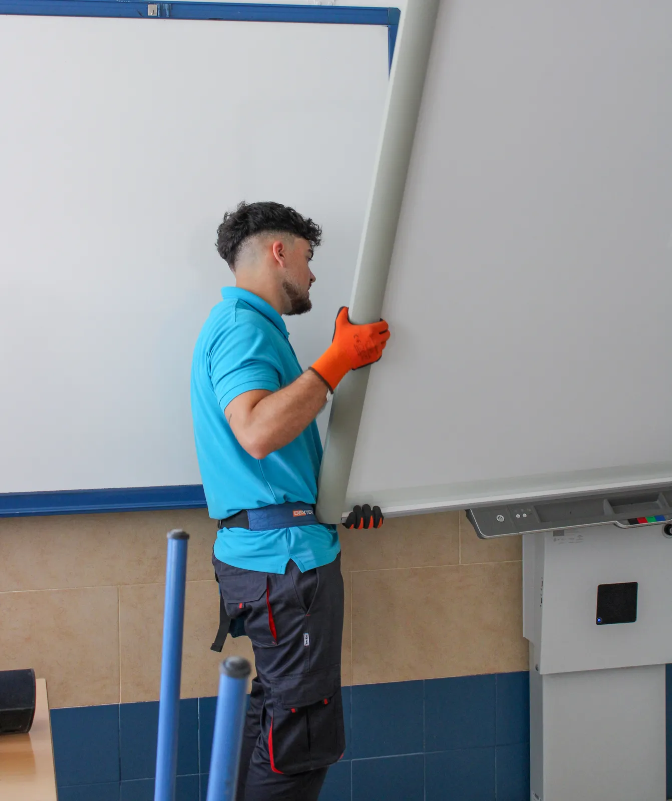 Técnico descolgando panel de pantalla a color en un aula
